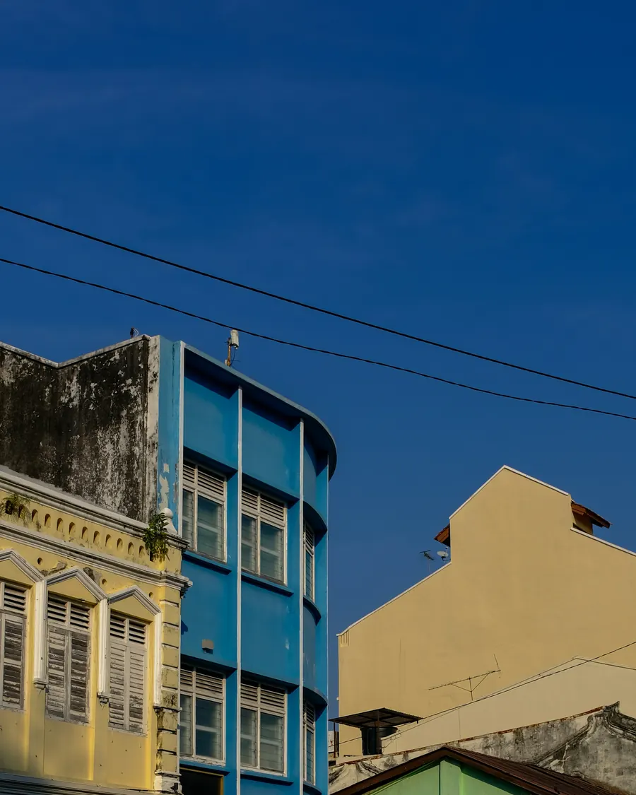Colourful heritage shophouses under a deep blue sky in George Town, Penang