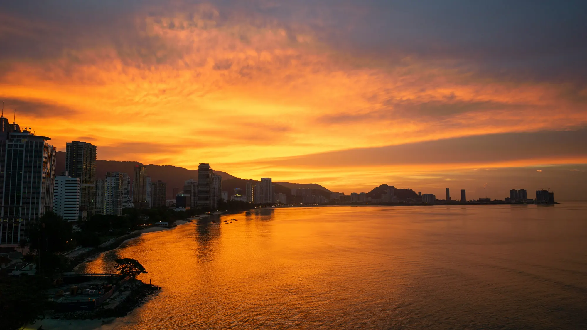 An orange sunset over the sea and the Penang coastline